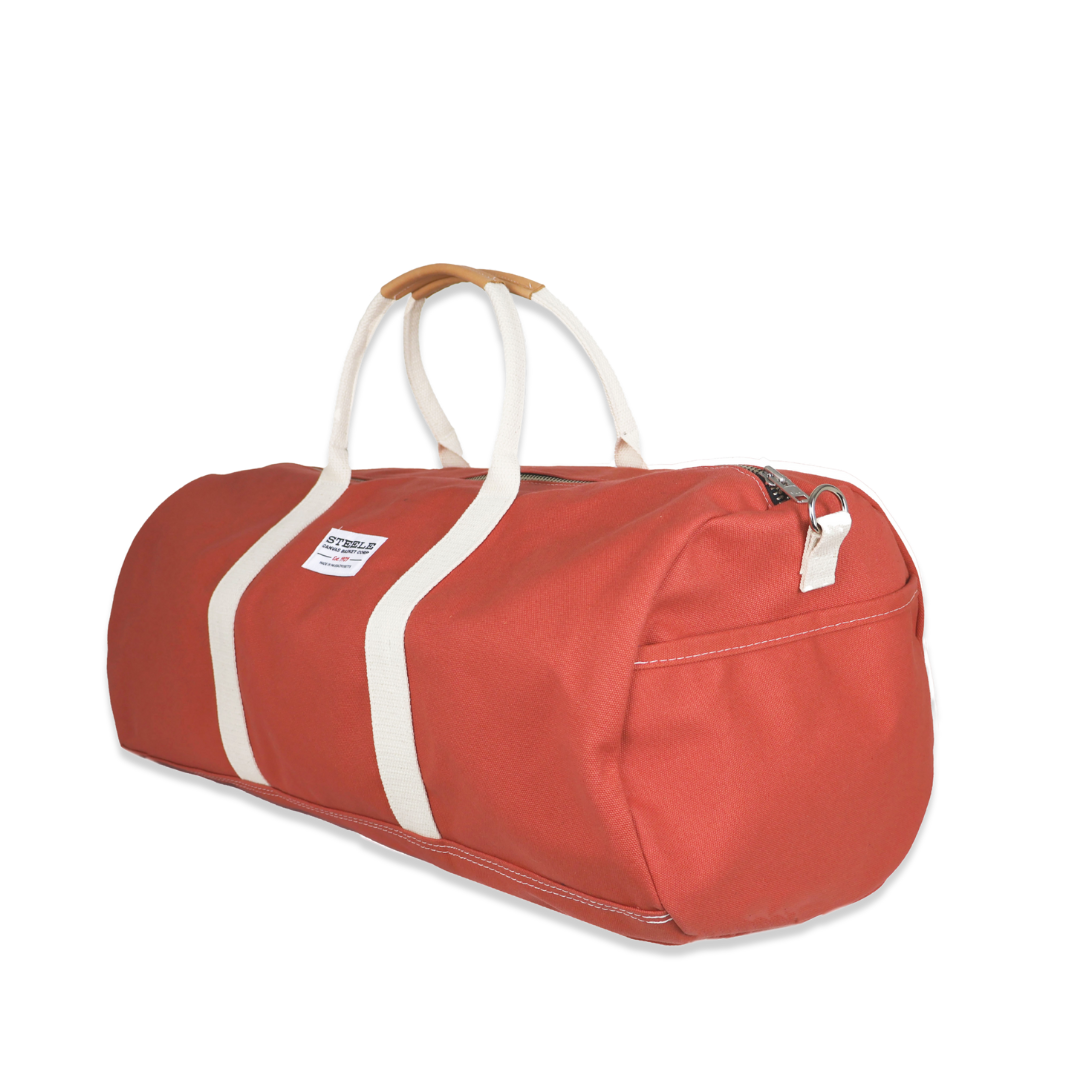 Red duffel bag with white straps on a white background
