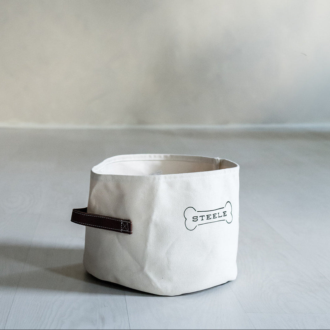 White fabric basket with brown handle on a light gray background