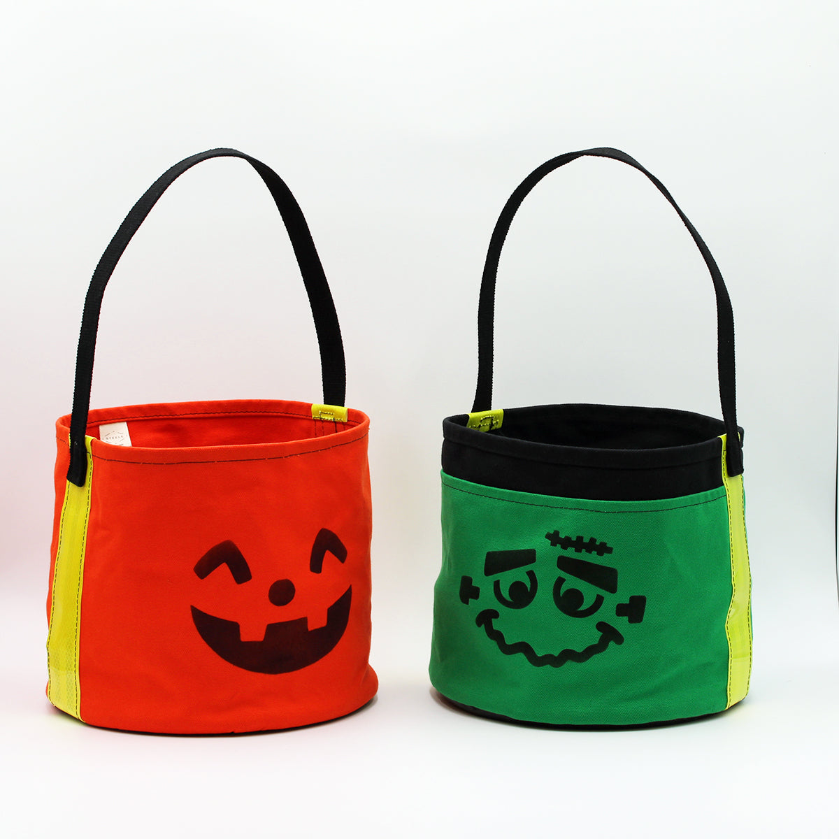 Two Halloween-themed buckets, one orange with a pumpkin face and one green with a Frankenstein face, on a white background.
