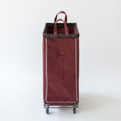 A tall, rectangular rolling storage cart in burgundy canvas with black trim, dual top handles, and a metal wheeled base, photographed against a plain white studio background.