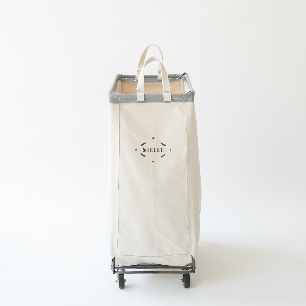 An off-white canvas laundry hamper with gray trim and black wheels, featuring a top handle and a black printed logo on the front, set against a plain white background.