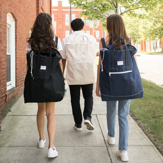 Three people walking outdoors with backpacks on a sidewalk.