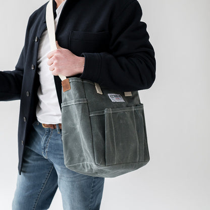 Person holding a gray shoulder bag against a plain background