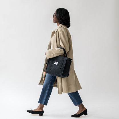 Woman walking with a black bag on a white background