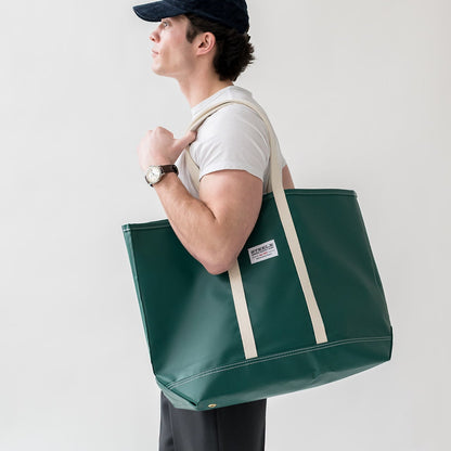 Man carrying a green tote bag with a white background