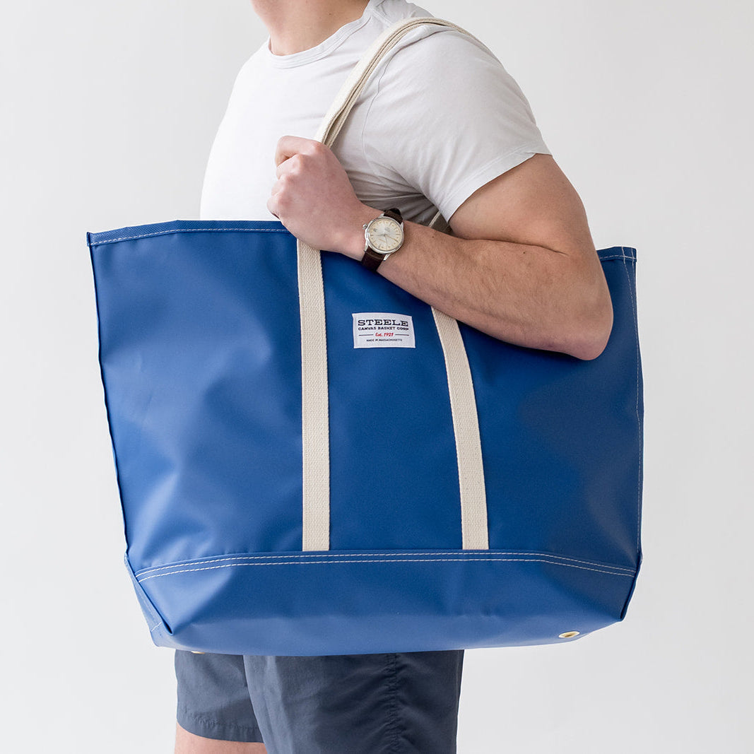 man holding a royal blue colored beach bag