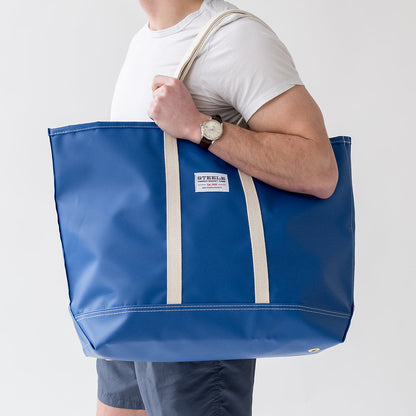 man holding a royal blue colored beach bag