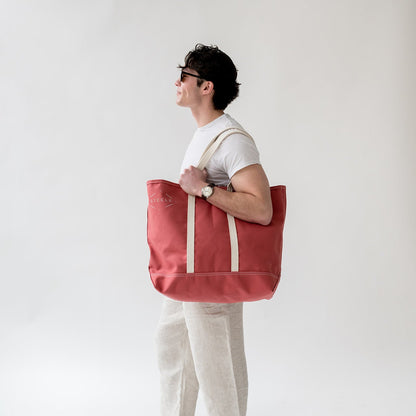 man holding a red tote bag at his side