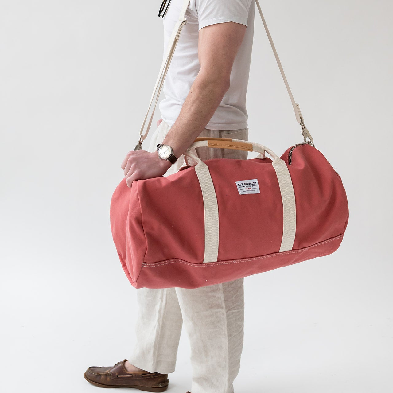 Person holding a red duffel bag with a white background