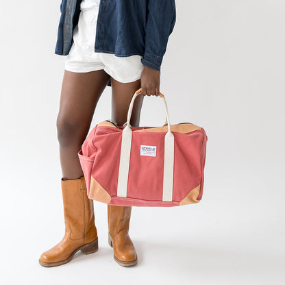 Person holding a pink duffel bag with a visible brand logo on a white background