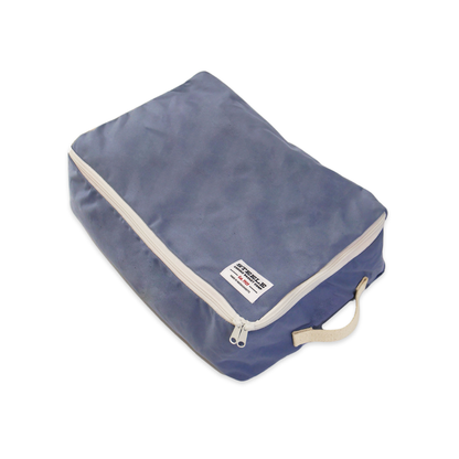 A blue zippered travel packing cube with a beige zipper trim and a small white brand label, shown on a plain white background.