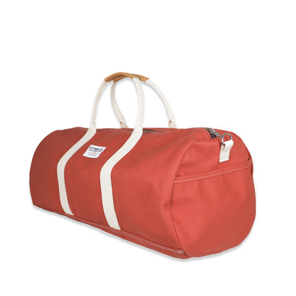 Red duffel bag with white straps on a white background