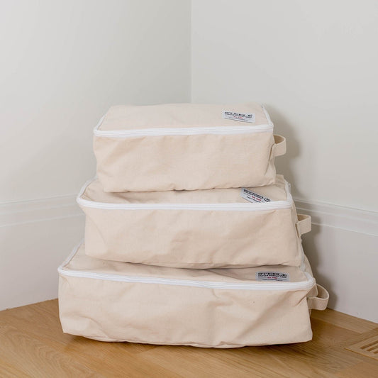 A set of beige canvas storage cubes in three different sizes, stacked on top of each other.