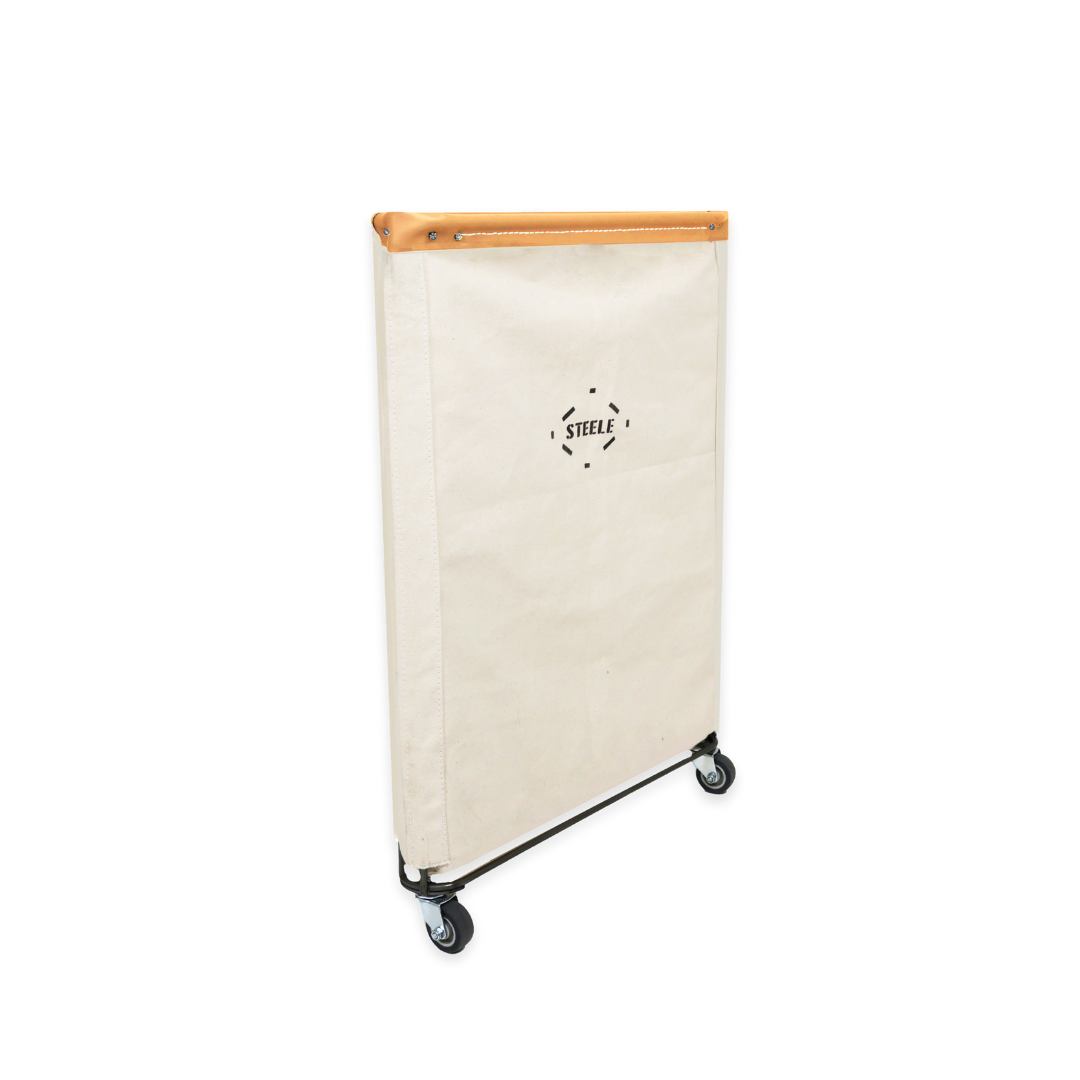 side angle of a natural canvas laundry hamper with a vegetable tan leather rim