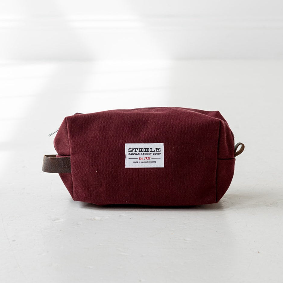 Maroon toiletry bag with a label on a white background