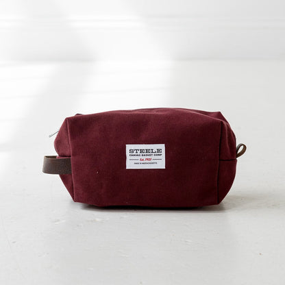 Maroon toiletry bag with a label on a white background