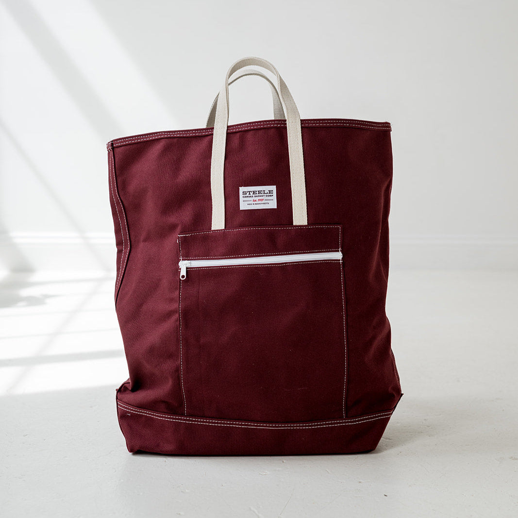Maroon tote bag with white handles on a light gray background