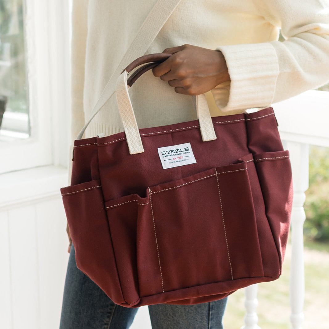 Person holding a auburn tool bag with a white label on a porch.