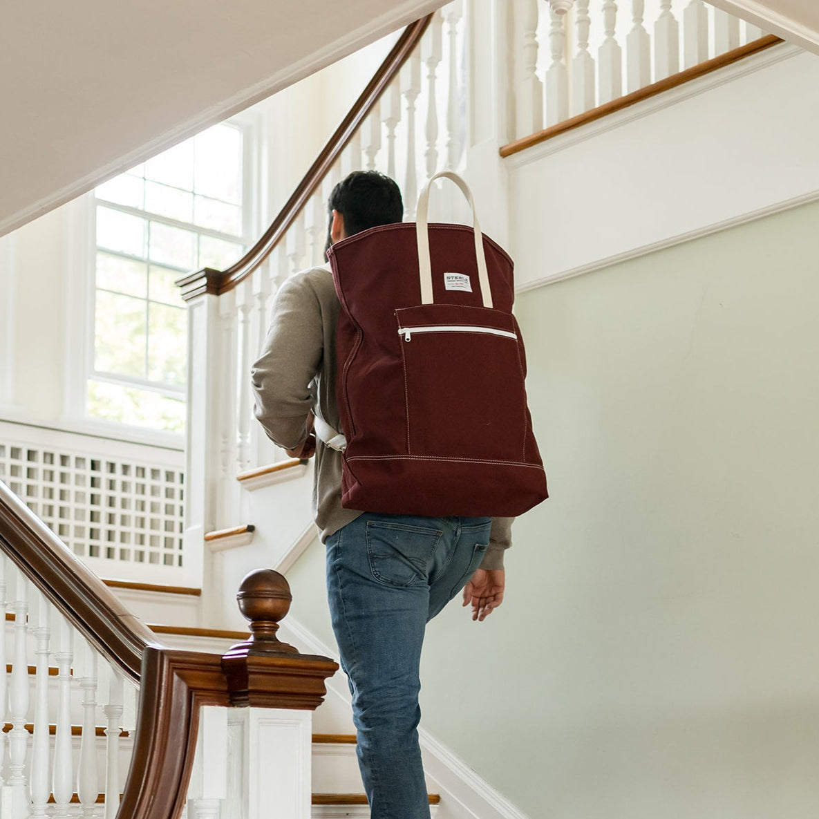 Person with a maroon backpack ascending a staircase
