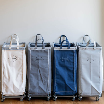 Four laundry baskets of different colors lined up against a white wall.