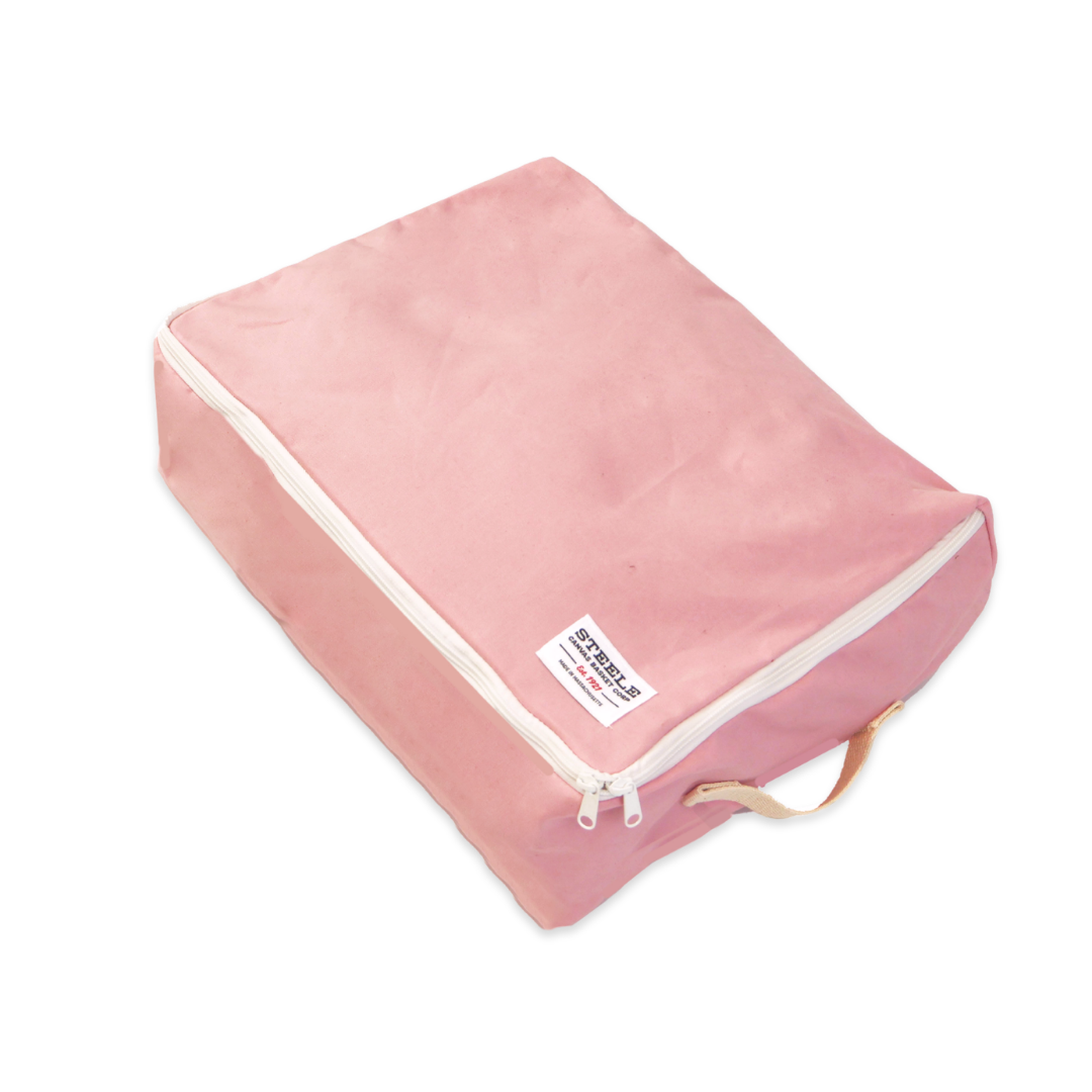 A pink canvas shoe bag with white zipper trim and a small white label, shown on a plain white background.