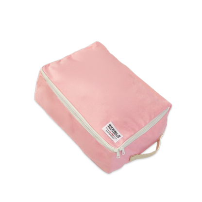 A pink canvas packing cube with a cream-colored zipper and a small white brand label that reads 'STEELE"