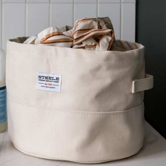 Beige fabric basket with a label on a tiled floor