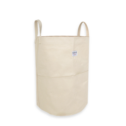 side angle of a tall canvas storage bag with handles on a white background