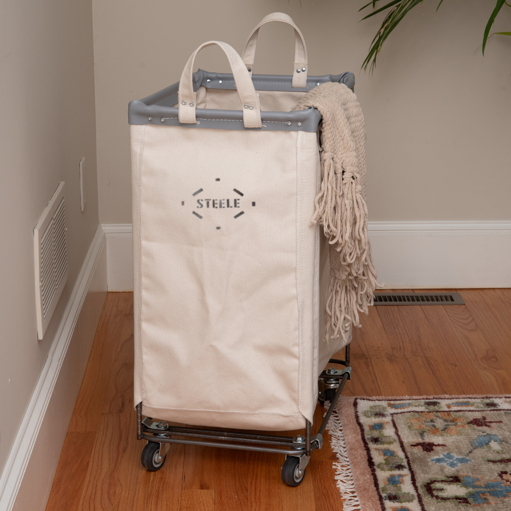 White bag with 'STELLE' logo on a cart next to a brown leather sofa and wooden crib.