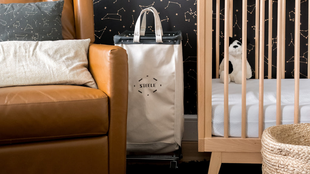 White bag with 'STELLE' logo on a cart next to a brown leather sofa and wooden crib.